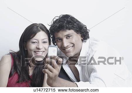 Stock Photography - Young couple looking at a mobile phone. Fotosearch