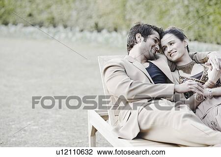 Stock Image - Young couple sitting in a garden. Fotosearch