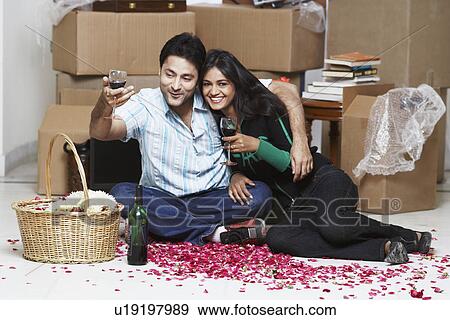 Young couple sitting on the floor holding wineglasses View Large Photo Image Stock Photo - Young couple sitting on the floor holding wineglasses. Fotosearch