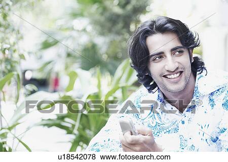 Close-up of a young man holding a mobile phone View Large Photo Image Stock Photo - Close-up of a young man holding a mobile phone. Fotosearch
