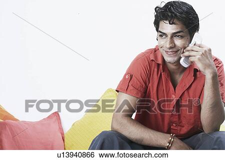 Close-up of a young man talking on a mobile phone View Large Photo Image Stock Photograph - Close-up of a young man talking on a mobile phone. Fotosearch