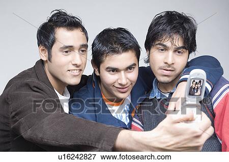 Close-up of three young men holding a mobile phone View Large Photo Image Stock Photo - Close-up of three young men holding a mobile phone. Fotosearch