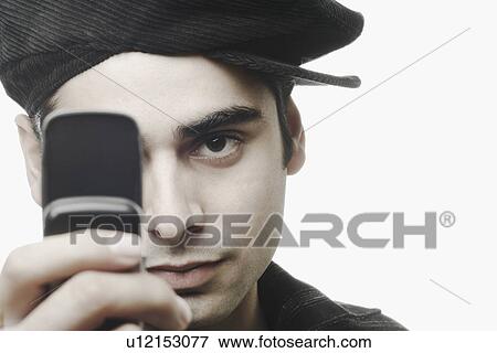 Portrait of a young man holding a mobile phone in front of his face View Large Photo Image Stock Photo - Portrait of a young man holding a mobile phone in front of his face. Fotosearch