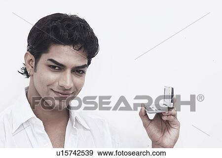 Stock Photo - Portrait of a young man holding a mobile phone. Fotosearch