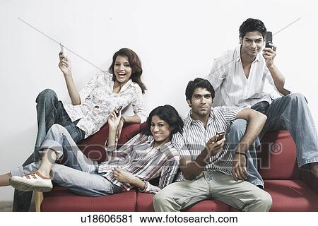 Stock Image - Portrait of two young women and two young men holding mobile phones. Fotosearch