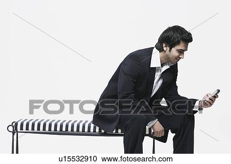 Young man operating a mobile phone View Large Photo Image Stock Image - Young man operating a mobile phone. Fotosearch