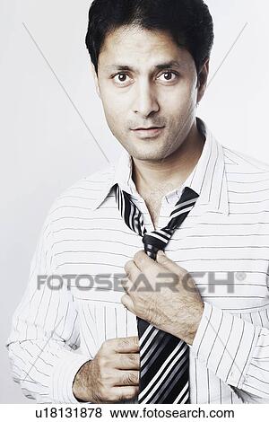 Portrait of a businessman adjusting his tie View Large Photo Image Stock Photo - Portrait of a businessman adjusting his tie. Fotosearch