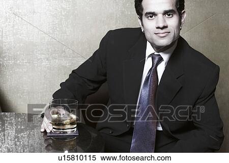 Stock Photography - Portrait of a businessman holding a glass of whiskey. Fotosearch