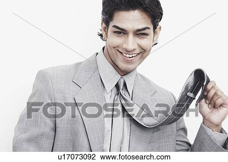 Stock Image - Portrait of a businessman holding his tie. Fotosearch