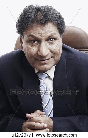 Stock Image - Portrait of a businessman sitting with his hands clasped. Fotosearch