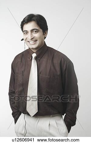 Stock Image - Portrait of a businessman using a hands free device. Fotosearch