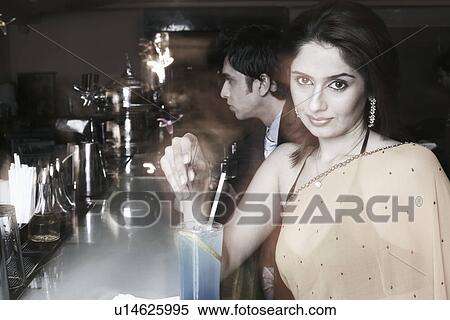 Stock Photography - Portrait of a businesswoman at a bar counter with a cocktail. Fotosearch