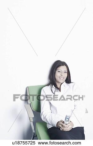 Portrait of a young woman holding a mobile phone View Large Photo Image Stock Photography - Portrait of a young woman holding a mobile phone. Fotosearch