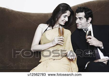 Stock Image - Young couple holding champagne flutes. Fotosearch