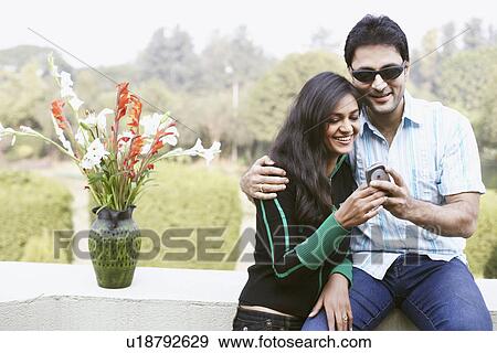 Close-up of a young couple looking at a mobile phone View Large Photo Image Stock Photo - Close-up of a young couple looking at a mobile phone. Fotosearch