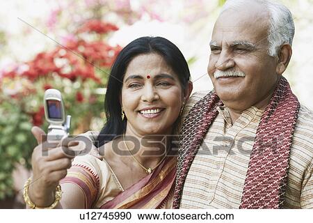 Close-up of mature couple looking at a mobile phone View Large Photo Image Stock Image - Close-up of mature couple looking at a mobile phone. Fotosearch
