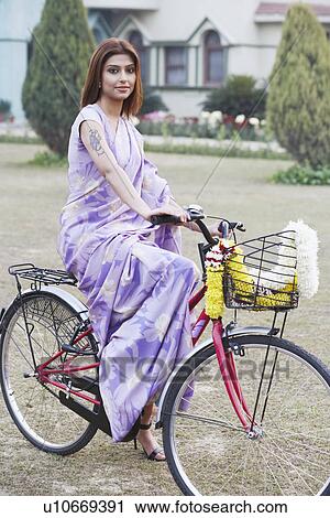 Stock Image - Portrait of a young woman riding a bicycle. Fotosearch