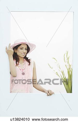 Stock Image - Portrait of a young woman standing near a window. Fotosearch