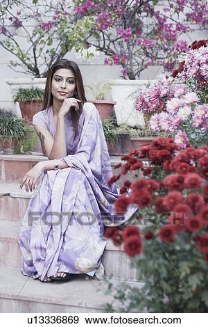 Portrait of a young woman with her hand on her chin sitting on steps View Large Photo Image Stock Photo - Portrait of a young woman with her hand on her chin sitting on steps. Fotosearch
