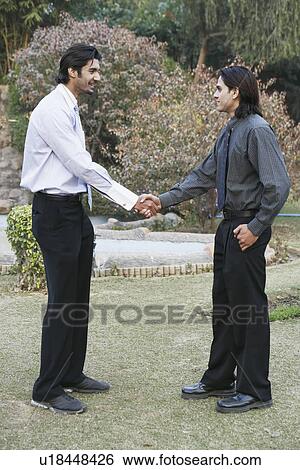 Stock Photograph - Side profile of two businessmen shaking hands. Fotosearch