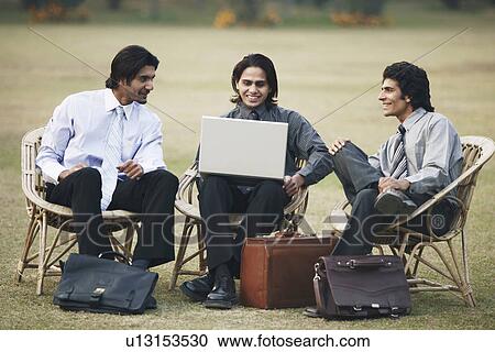 Stock Image - Three businessmen using a laptop. Fotosearch
