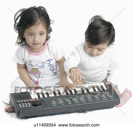 Picture - Close-up of a baby boy and his sister playing an electric piano. Fotosearch