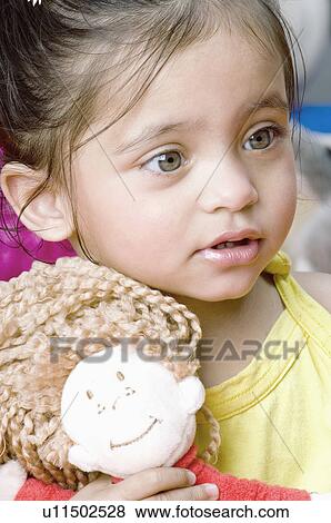 Close-up of a baby girl holding a doll View Large Photo Image Stock Photo - Close-up of a baby girl holding a doll. Fotosearch