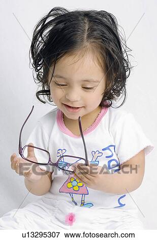 Close-up of a baby girl holding a pair of eyeglasses View Large Photo Image Stock Photo - Close-up of a baby girl holding a pair of eyeglasses. Fotosearch
