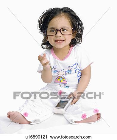 Stock Image - Close-up of a baby girl holding a mobile phone. Fotosearch