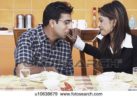 Close-up of a young couple sharing a noodle View Large Photo Image Stock Photo - Close-up of a young couple sharing a noodle. Fotosearch