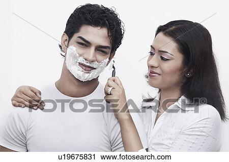Close-up of a young woman shaving a young man View Large Photo Image Stock Image - Close-up of a young woman shaving a young man. Fotosearch