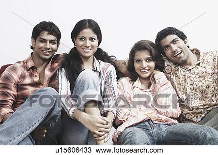 Close-up of two young couples sitting together on a couch smiling View Large Photo Image Stock Image - Close-up of two young couples sitting together on a couch smiling. Fotosearch
