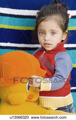 Stock Image - Portrait of a baby girl holding a stuffed toy. Fotosearch