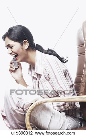 Stock Image - Side profile of a businesswoman talking on a mobile phone. Fotosearch