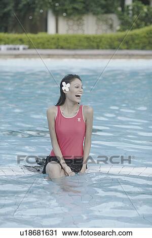 Stock Image - Young woman sitting in a swimming pool. Fotosearch
