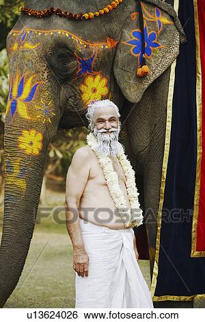 Stock Photograph - Priest standing beside an elephant. Fotosearch