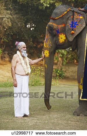 Stock Photo - Priest touching the trunk of an elephant. Fotosearch