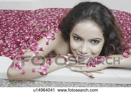 Stock Image - Portrait of a young woman in a bathtub covered with flower petals. Fotosearch