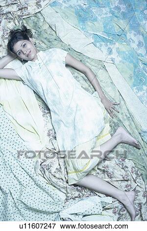 Stock Photo - Portrait of a young woman lying on fabric. Fotosearch
