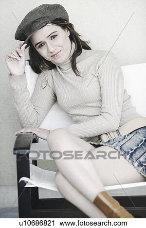 Portrait of a young woman sitting with her legs crossed View Large Photo Image Stock Image - Portrait of a young woman sitting with her legs crossed. Fotosearch