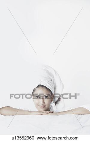 Stock Image - Portrait of a young woman with a towel wrapped around her head. Fotosearch