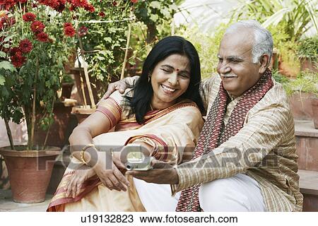 Close-up of a mature couple looking at a digital camera View Large Photo Image Stock Image - Close-up of a mature couple looking at a digital camera. Fotosearch