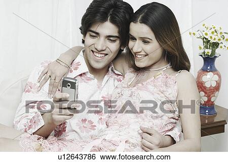 Stock Photograph - Close-up of a young couple looking at a mobile phone. Fotosearch