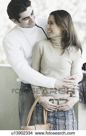 Close-up of a young man embracing a young woman from behind View Large Photo Image Picture - Close-up of a young man embracing a young woman from behind. Fotosearch