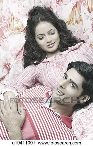 Stock Image - High angle view of a young couple lying down. Fotosearch