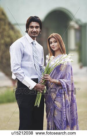 Portrait of a young couple holding a bouquet of flowers View Large Photo Image Stock Photo - Portrait of a young couple holding a bouquet of flowers. Fotosearch