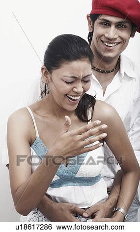 Stock Photograph - Portrait of a young man embracing a young woman from behind. Fotosearch