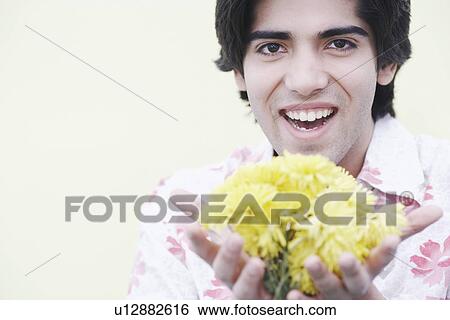Stock Photograph - Portrait of a young man holding flowers. Fotosearch