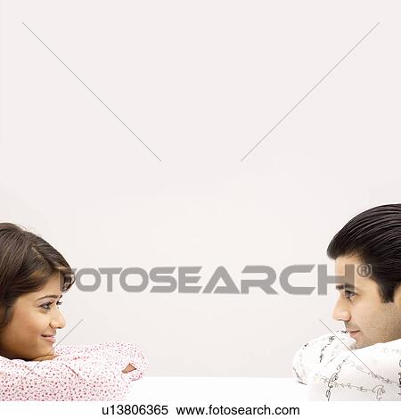 Side profile of a young couple looking at each other View Large Photo Image Stock Photography - Side profile of a young couple looking at each other. Fotosearch