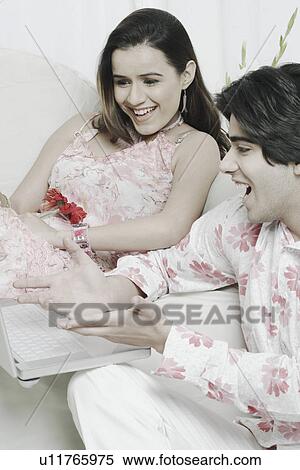 Stock Photography - Young couple looking at a laptop. Fotosearch